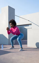 Schwarze Sportlerin macht Kniebeugen beim Training - CAVF95319