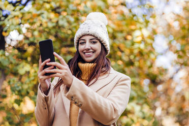 Junge Frau hält Smartphone im Park - EBBF04828