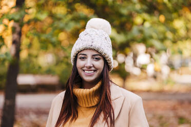 Young woman wearing knit hat at autumn park - EBBF04830