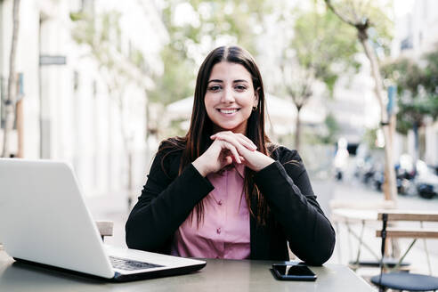 Young businesswoman with laptop at sidewalk cafe - EBBF04833