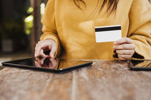 Young woman using digital tablet at cafe table - EBBF04856