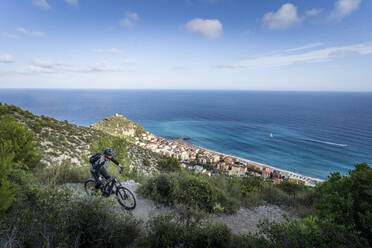 Sportlerin beim Radfahren auf einem Berg inmitten von Pflanzen - MALF00362