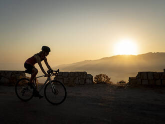 Sportlerin fährt Mountainbike bei Sonnenuntergang - MALF00385