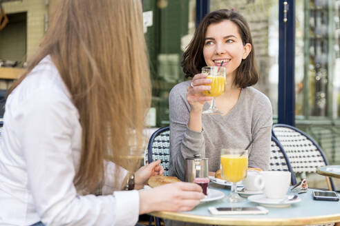 Lächelnde Frau trinkt Saft mit einem Freund in einem Cafe - WPEF05506