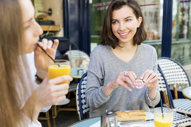 Lächelnde Frau, die einen Freund ansieht, der in einem Café Saft trinkt - WPEF05508