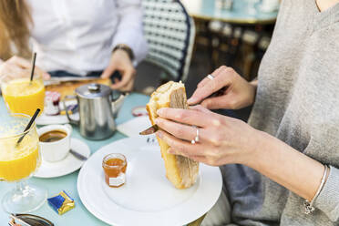 Junge Frau schneidet Baguette auf einem Teller im Café - WPEF05510