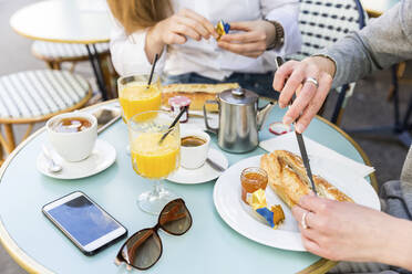 Frau trägt in einem Café Butter auf ein Baguette auf - WPEF05511