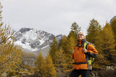 Lächelnder älterer Mann mit Rucksack beim Wandern in den Rätischen Alpen, Italien - MRAF00766