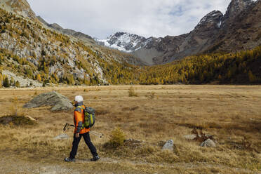 Senior tourist with pole hiking on mountain at Rhaetian Alps, Italy - MRAF00767