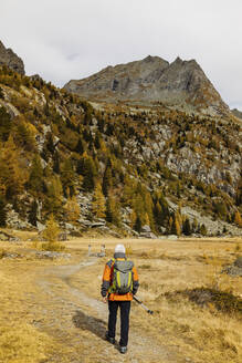 Älterer Tourist mit Rucksack beim Wandern auf einem Berg in den Rätischen Alpen, Italien - MRAF00768