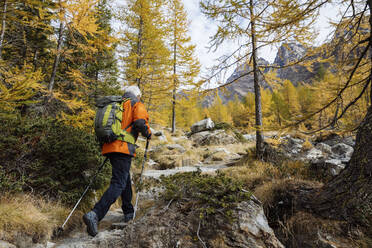 Senior man hiking on mountain at Rhaetian Alps, Italy - MRAF00778