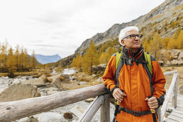 Senior man looking away from wooden bridge at Rhaetian Alps, Italy - MRAF00787