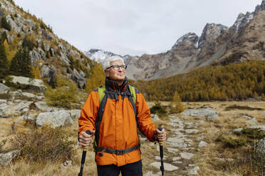 Lächelnder Wanderer mit Wanderstöcken auf einem Berg in den Rätischen Alpen, Italien - MRAF00796