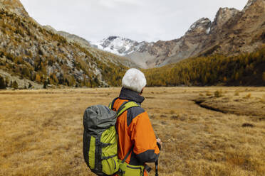 Älterer Rucksacktourist mit Blick auf die Berge in den Rätischen Alpen, Italien - MRAF00797