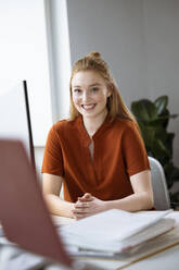 Smiling businesswoman sitting at desk - FKF04559