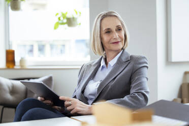 Blonde Geschäftsfrau mit Tablet-PC am Arbeitsplatz - FKF04569