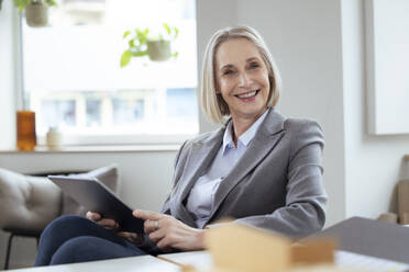 Lächelnde Geschäftsfrau mit Tablet-PC im Büro - FKF04570