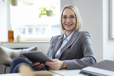 Geschäftsfrau mit Brille hält Tablet-PC im Büro - FKF04571