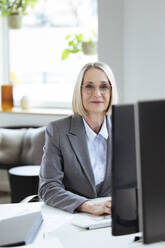 Senior businesswoman sitting at desk - FKF04573