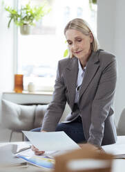 Ältere Geschäftsfrau beim Lesen eines Dokuments im Büro - FKF04578