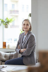 Senior businesswoman with arms crossed at desk - FKF04580