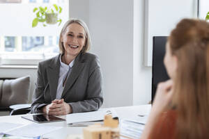 Senior businesswoman discussing with colleague in office - FKF04597