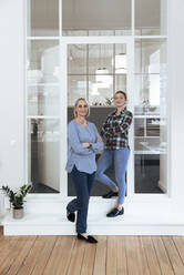 Businesswomen with arms crossed at office door - FKF04616