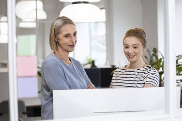 Geschäftsfrauen bei einer Diskussion hinter Glas im Büro - FKF04623