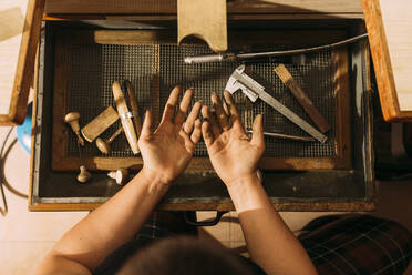 Schmutzige Hände eines weiblichen Handwerkers vor Arbeitsgeräten in einer Werkstatt - GPF00229