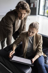 Businesswoman discussing with colleague over tablet PC in lobby - PESF03278