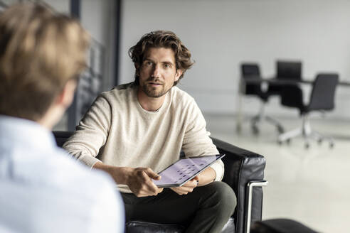 Businessman with tablet pc looking at colleague in lobby - PESF03299