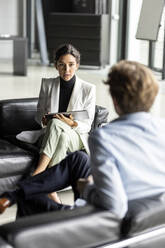 Businesswoman discussing with businessman in lobby - PESF03309