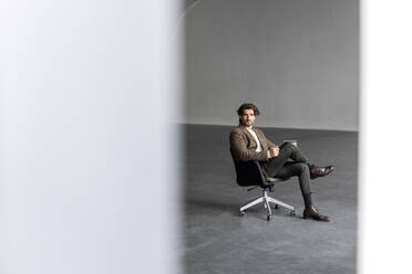 Businessman with tablet pc on chair at industrial hall - PESF03340