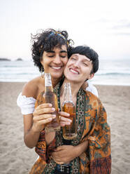 Liebendes multiethnisches Frauenpaar trinkt Bier und genießt den Sommertag am Meer - ADSF31704