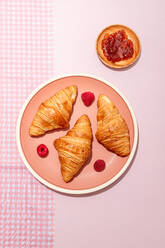 Von oben der Zusammensetzung der plated mit frisch gebackenen süßen Croissants serviert mit Beeren und Marmelade auf rosa Tisch platziert - ADSF31743