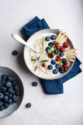 Draufsicht auf eine Schüssel mit köstlichem Haferbrei mit Blaubeeren und Himbeeren in der Nähe von Birnenscheiben, die beim Frühstück auf dem Tisch stehen - ADSF31747