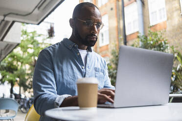 Mann mit Laptop am Tisch in einem Straßencafé - ASGF01804