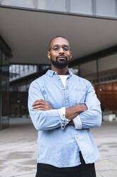 Man in casual clothing standing with arms crossed near buildings - ASGF01816