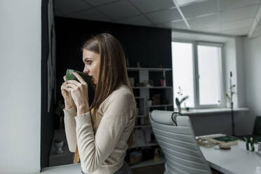 Geschäftsfrau trinkt Kaffee im Büro - LLUF00382