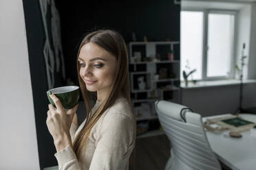 Geschäftsfrau mit langen Haaren hält Kaffeetasse im Büro - LLUF00383