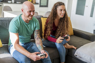 Smiling couple playing video games at home - DLTSF02406