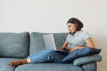 Young female freelancer working on laptop in living room at home - MEUF04725