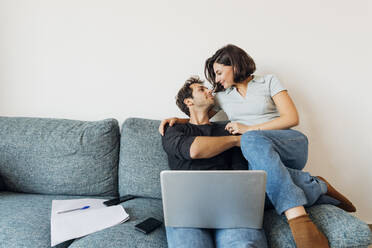 Smiling young couple looking at each other while working at home - MEUF04737