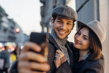 Smiling young woman and man in hat taking selfie - MEUF04771