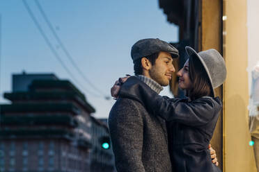Young couple looking at each other while embracing near store - MEUF04774