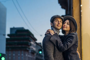 Young couple in hat embracing in city - MEUF04775