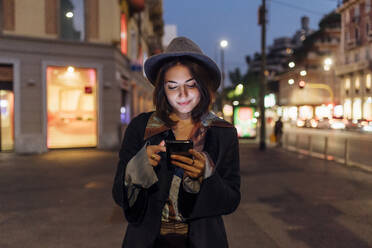 Smiling young woman using smart phone on city street - MEUF04788