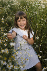 Smiling girl playing amidst flowers in meadow - SSGF00281