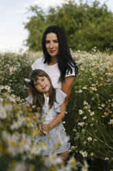 Mutter und Tochter stehen inmitten von Blumen auf einer Wiese - SSGF00283