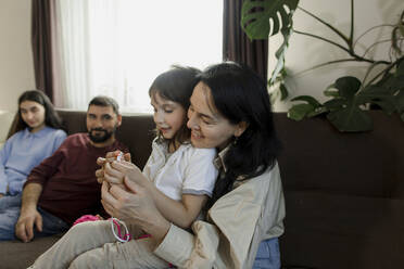 Mother teaching daughter crocheting wool at home - LLUF00417